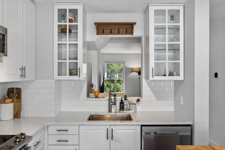 Contemporary kitchen featuring white cabinetry with brushed nickel hardware, subway tile backsplash, and light-toned countertops