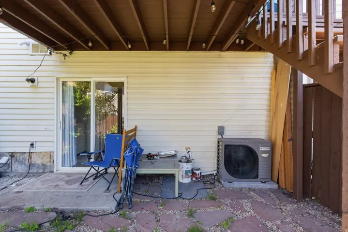 Lower-level patio area featuring a sliding glass door entry, stone paver ground covering, and a partial privacy fence