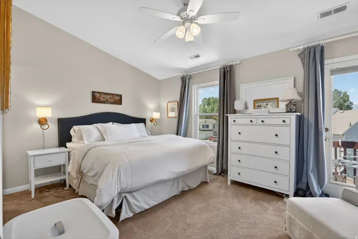 Bedroom featuring a vaulted ceiling, wall-mounted sconce lighting, ceiling fan, and carpeted flooring