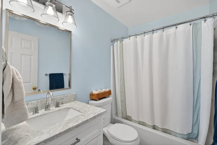 Bathroom featuring a single vanity with stone-finish countertop, undermount sink, and polished chrome faucet