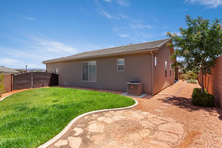 Expansive backyard featuring a manicured lawn area, flagstone patio, and gravel landscaping