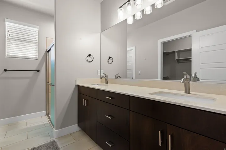 Dual vanity with dark wood-finish cabinetry, integrated sinks, and brushed nickel faucets