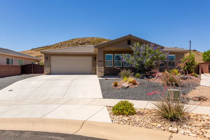 Contemporary stucco exterior with stone accents, a two-car garage, and a concrete driveway