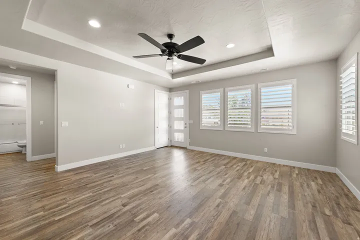 Spacious room with wood-finish flooring, tray ceiling, and recessed lighting