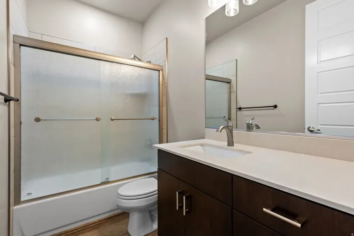 Bathroom vanity featuring a light-toned countertop, integrated sink, and dark wood-finish cabinetry with brushed nickel hardware