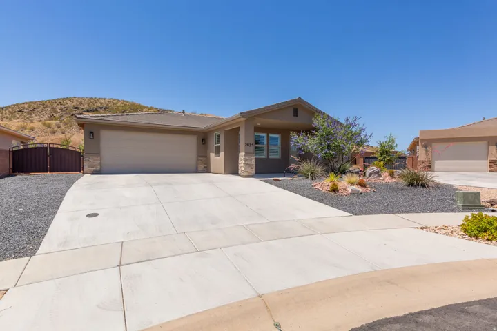 Single-story residence featuring a two-car garage, stone veneer accents, and a low-maintenance xeriscape front yard