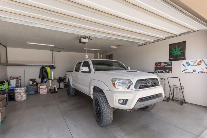 Spacious garage featuring a concrete floor, overhead garage door system, and wall-mounted shelving