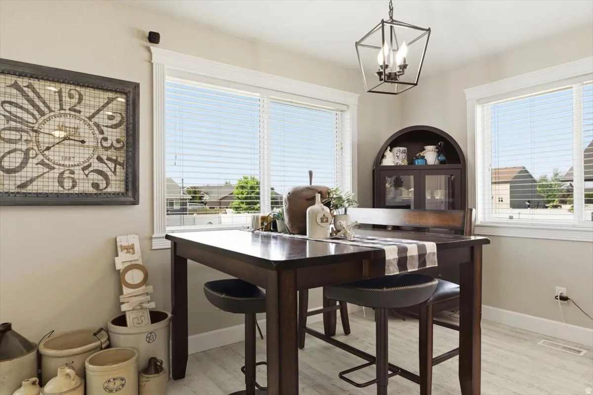 Dining area featuring two large windows with horizontal blinds, a dark wood-finish dining table, and light wood-finish flooring