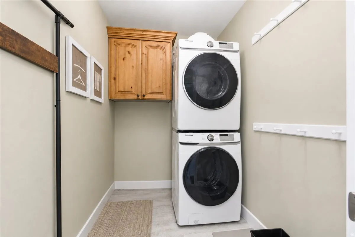 Dedicated utility space featuring a stacked washer and dryer, wood-finish cabinetry, and light gray flooring