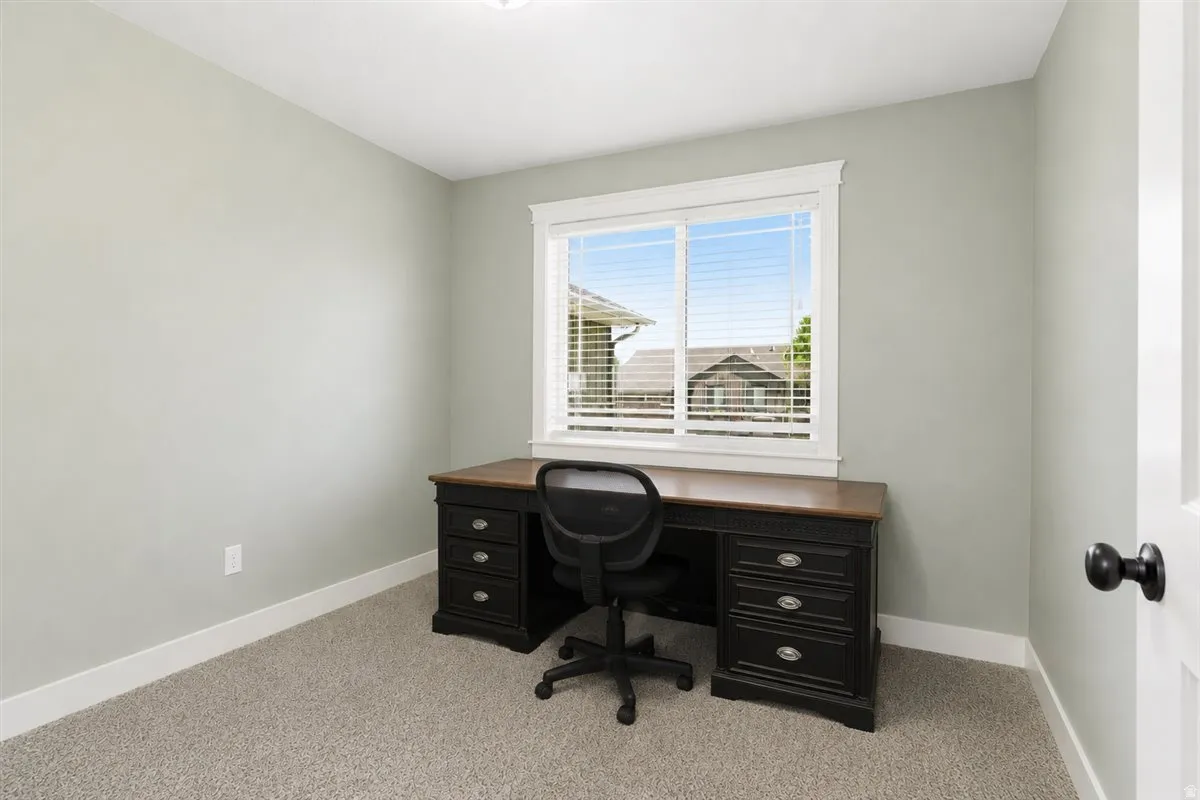 Neutral-toned room featuring a large window with white blinds, light gray walls, white trim, and carpeted flooring