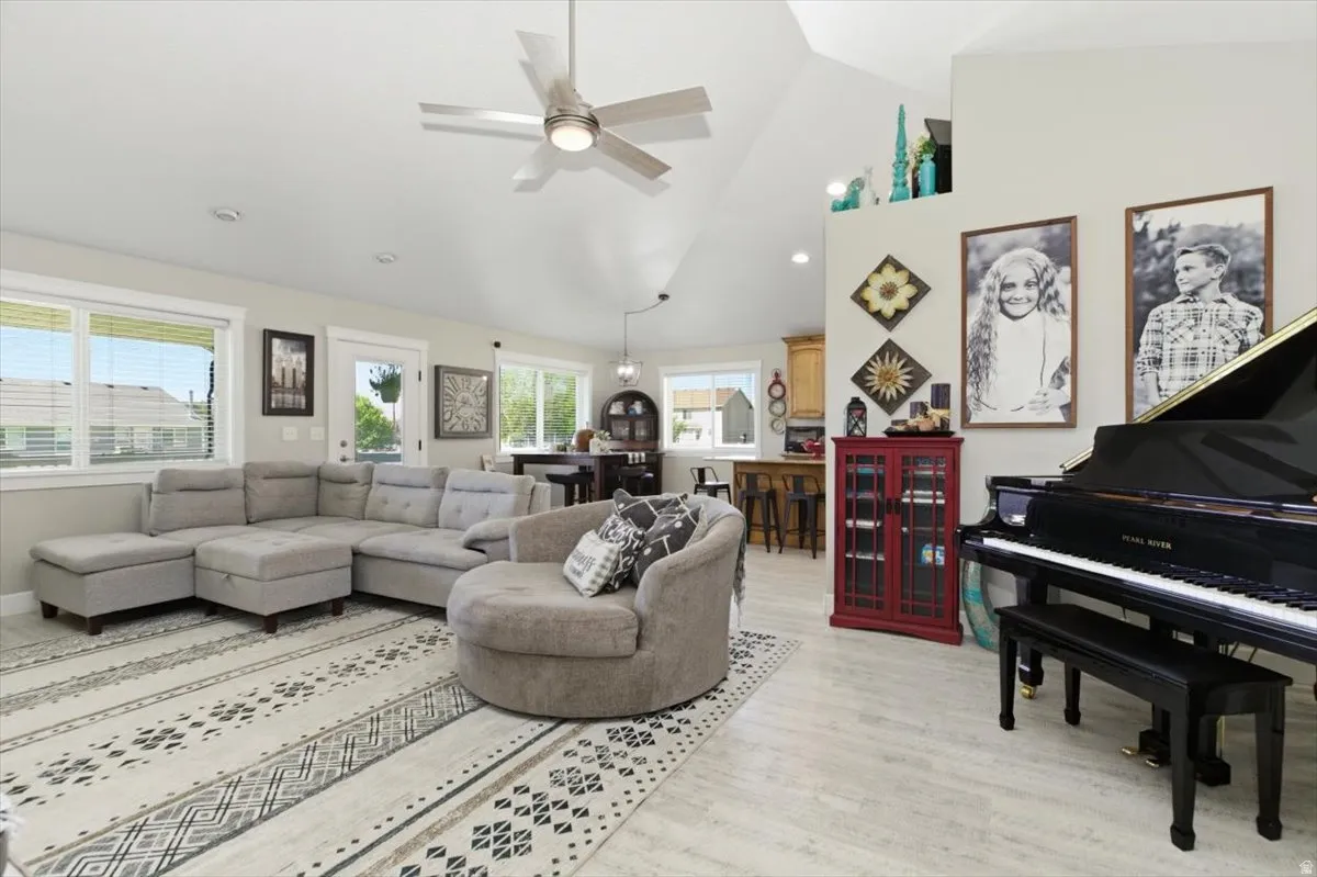Vaulted ceilings featuring a modern ceiling fan, wood-finish flooring, and multiple windows