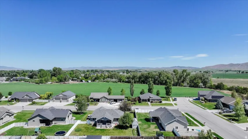 Expansive green spaces surround this residential street with multiple single-story homes featuring dark shingle roofs