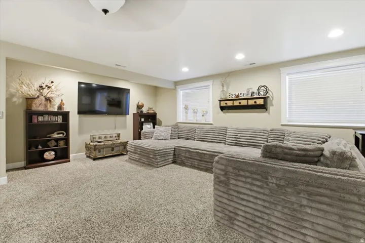 Spacious living area featuring neutral-toned walls, recessed lighting, and a textured carpet