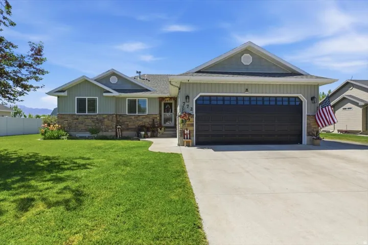 Ranch-style residence featuring a stone and siding exterior, a two-car garage with transom windows, and a concrete driveway