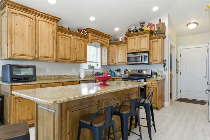 Kitchen featuring knotty wood cabinetry, granite countertops, stainless steel appliances, a center island with bar seating, and recessed lighting