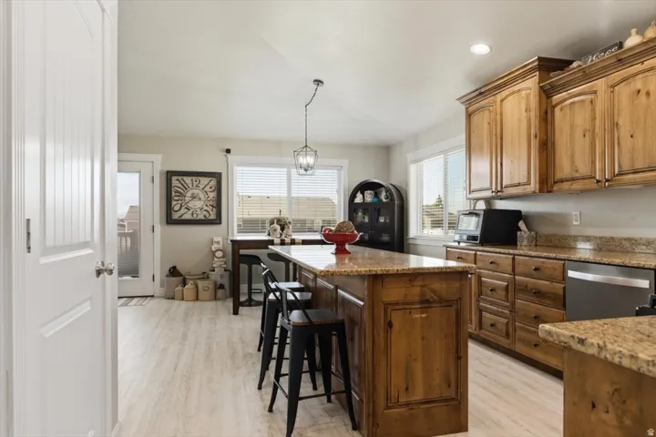 Kitchen featuring wood-finish cabinetry, granite countertops, and light wood-finish flooring