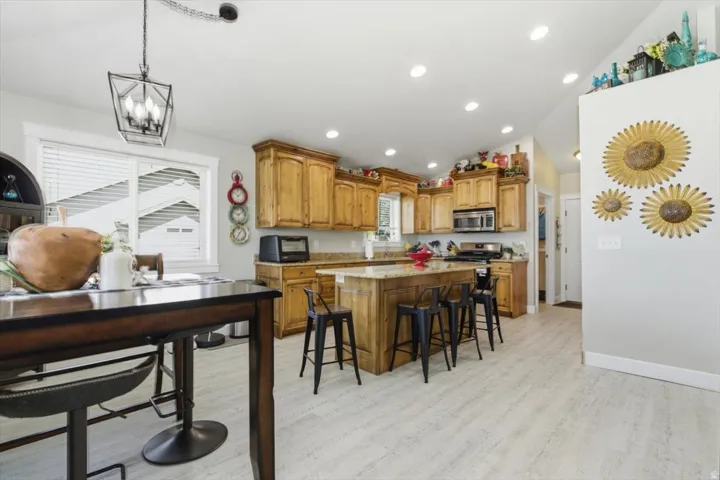 Kitchen featuring wood cabinetry, light-colored countertops, stainless steel appliances, and wood-finish flooring