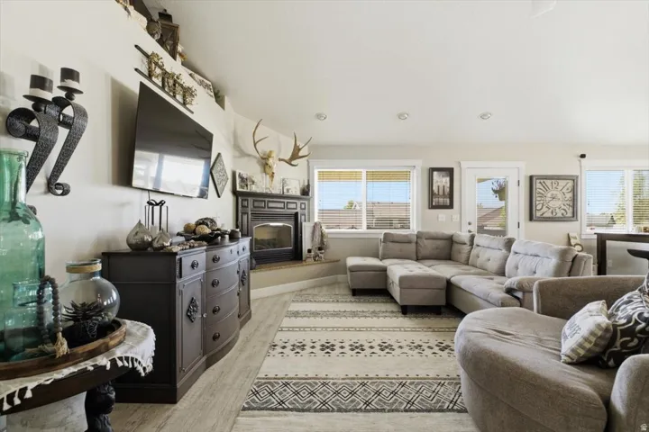 Spacious living area featuring light wood-finish flooring, recessed lighting, and multiple windows with blinds