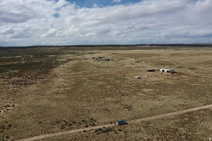 Expansive desert landscape featuring a dirt road and distant structures
