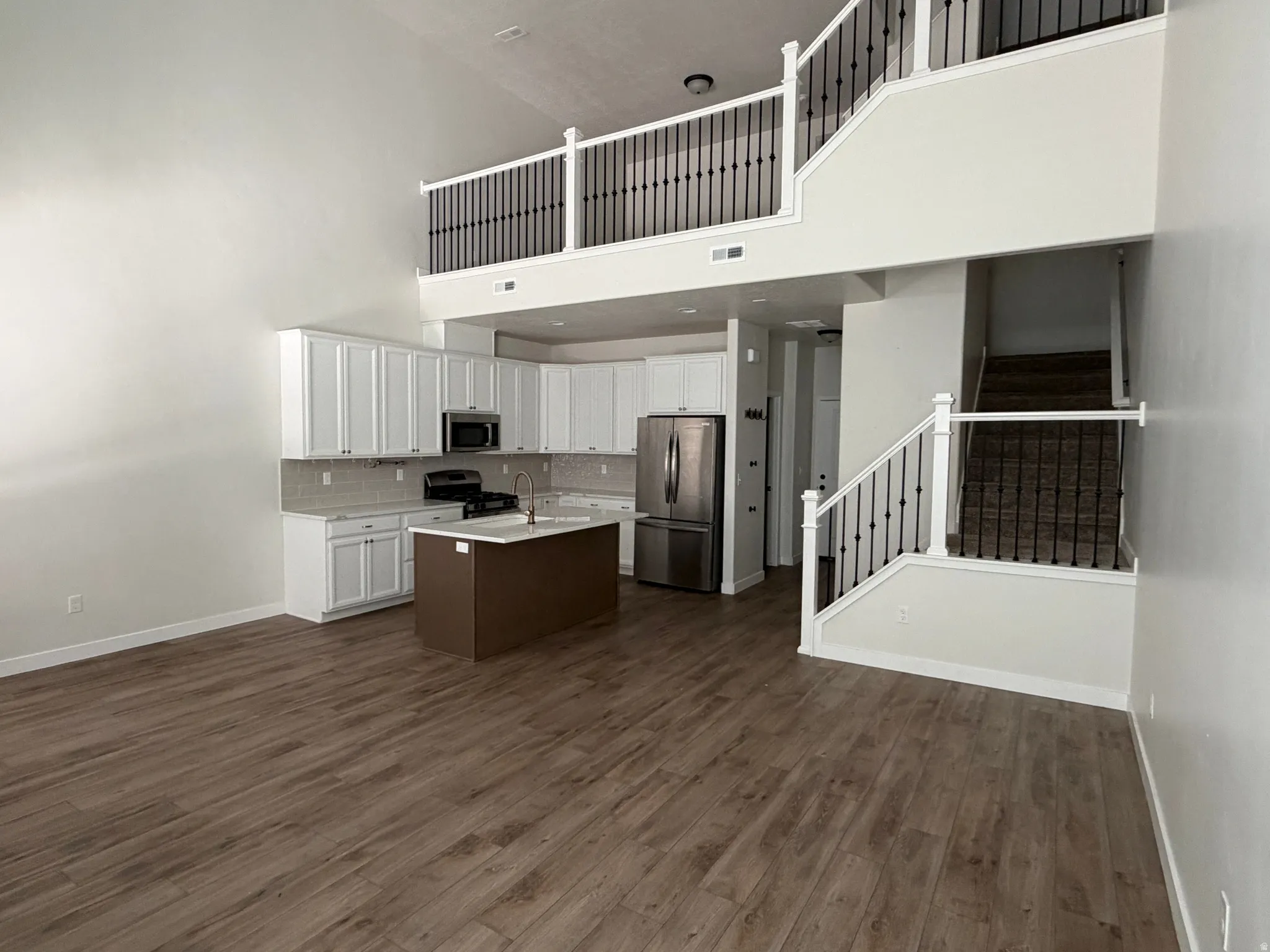 Open-concept living space featuring wood-finish flooring and high ceilings