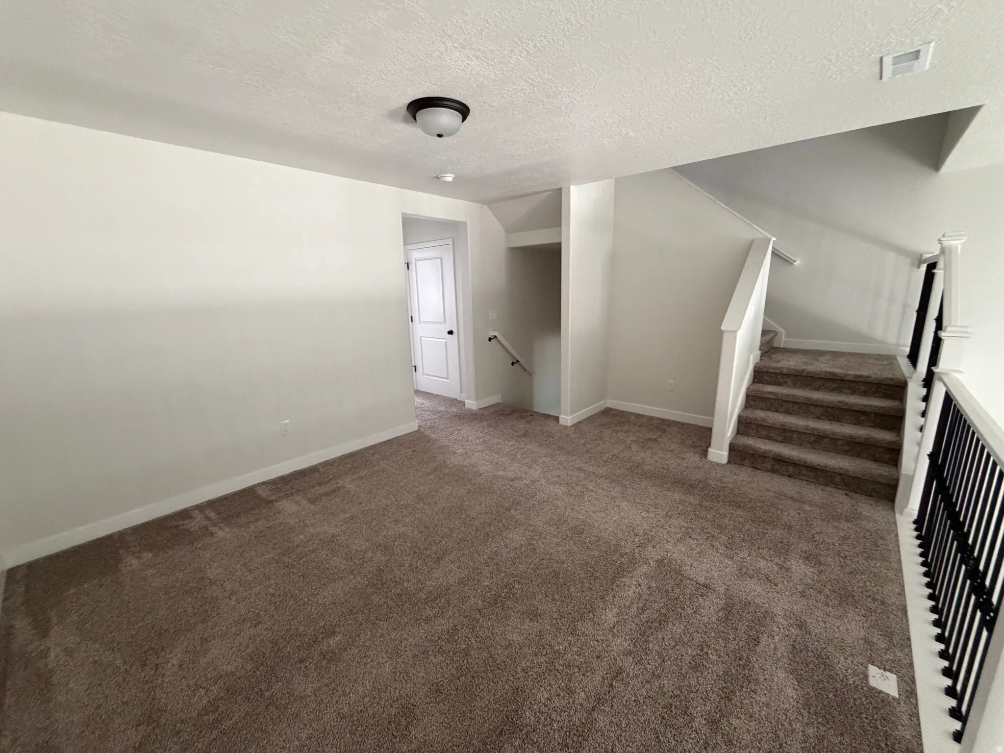 Carpeted landing featuring a white painted door, white baseboards, and a semi-flush mount ceiling light