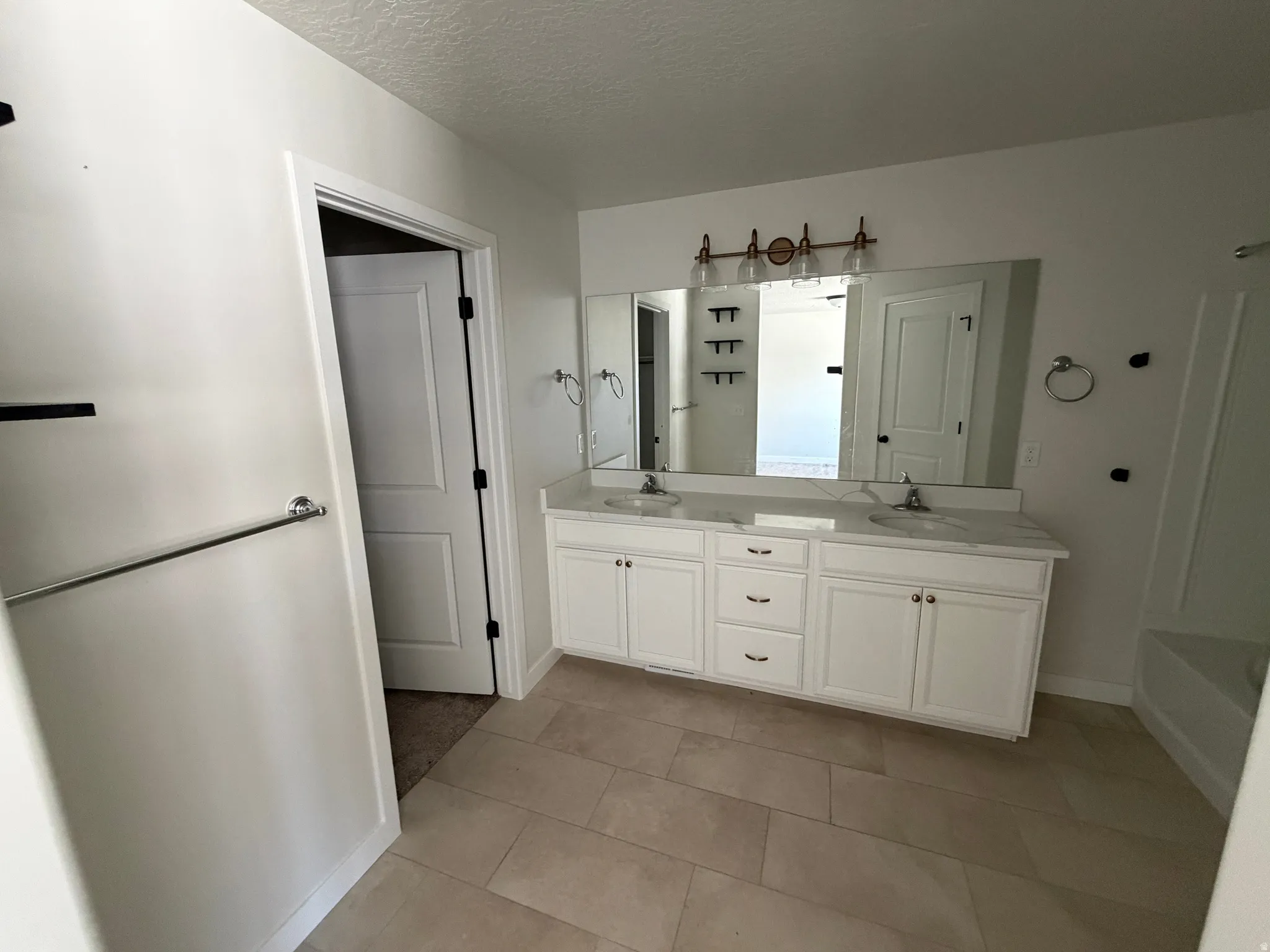 Bathroom featuring a double vanity with white cabinetry, light-toned countertop, and two undermount sinks