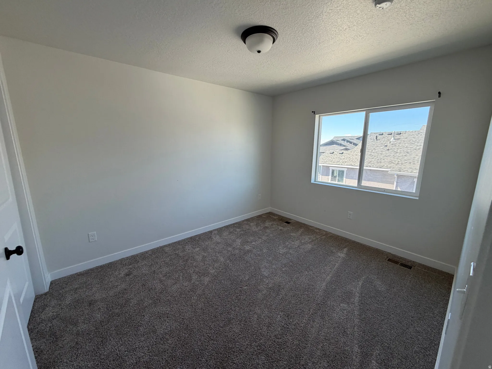 Room featuring broadloom carpeting, crisp white walls, and a large window with white trim
