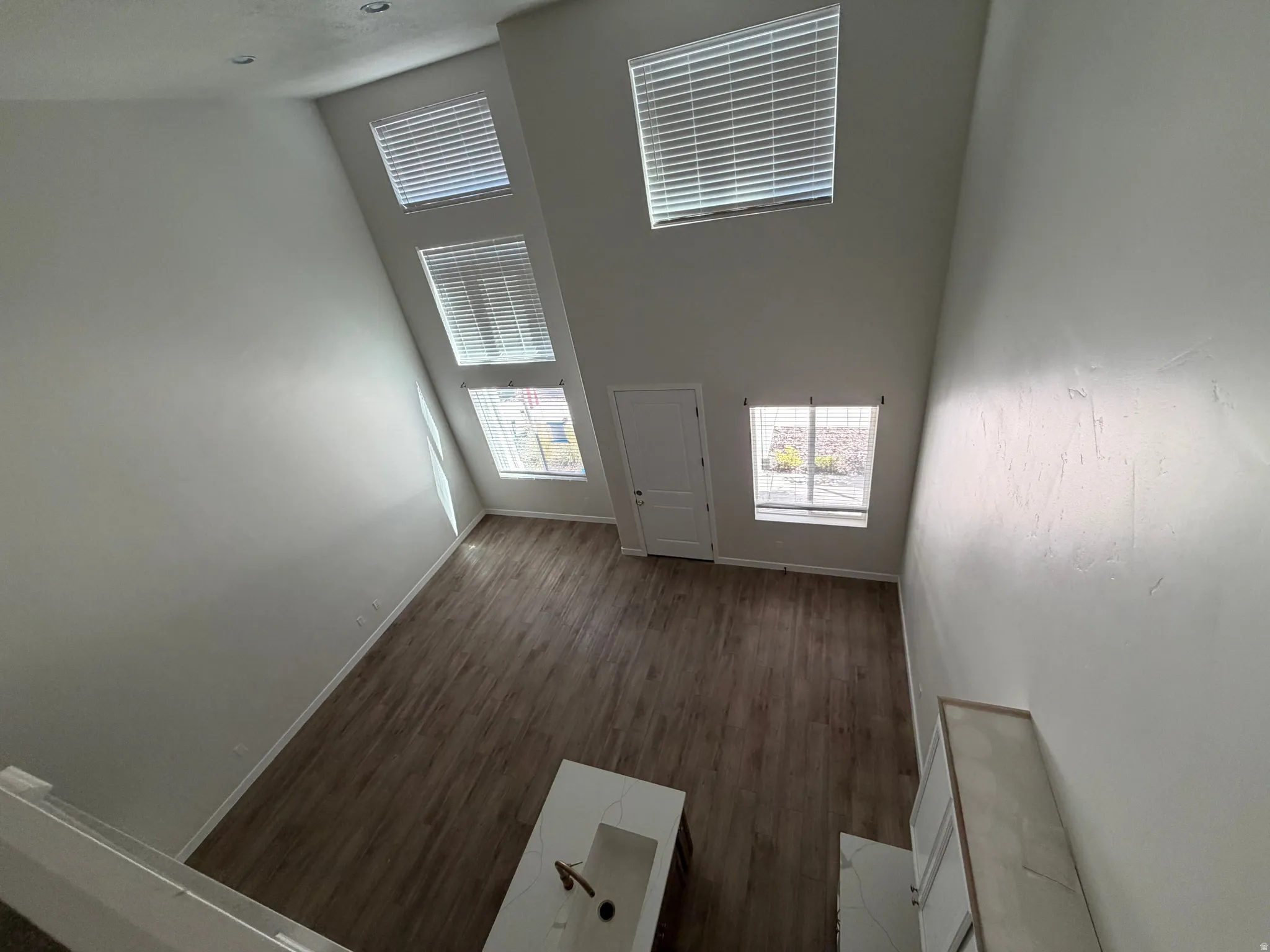 Two-story living area featuring wood-finish flooring and a vaulted ceiling with multiple windows