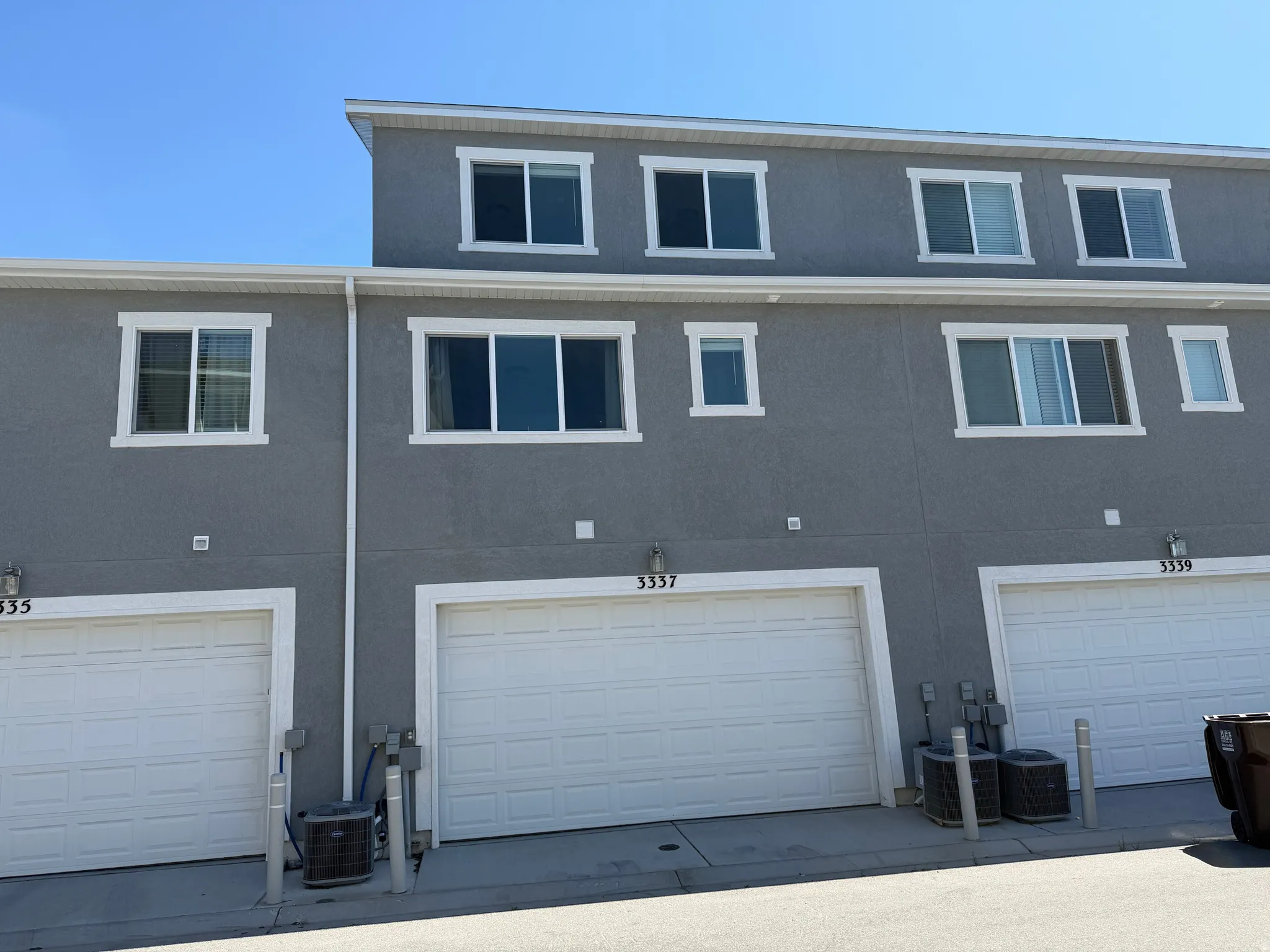 Multi-level townhouse exterior featuring a gray stucco facade and white trim