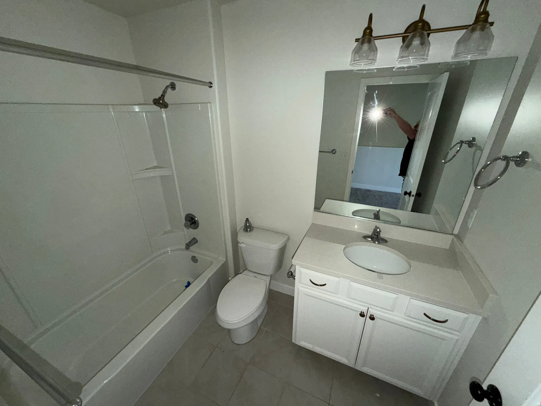 Bathroom featuring a white vanity with an oval sink, light-colored countertop, and two-door cabinetry with dark hardware