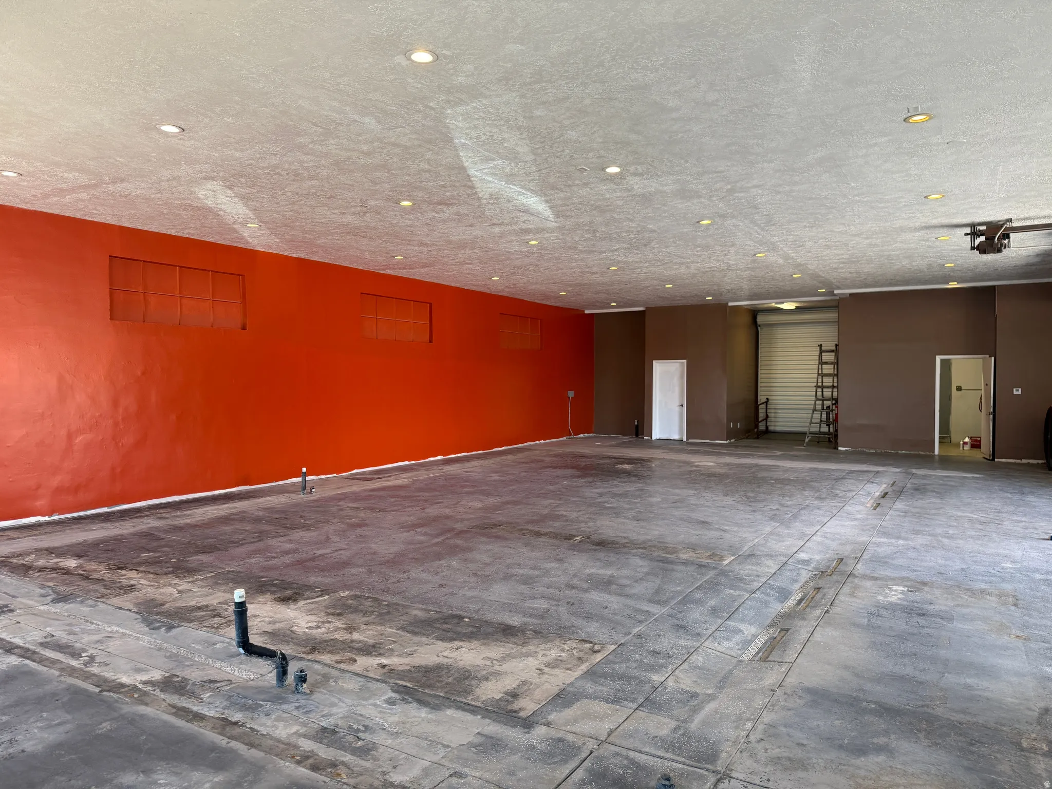 Spacious commercial interior featuring concrete flooring and a high ceiling with recessed lighting