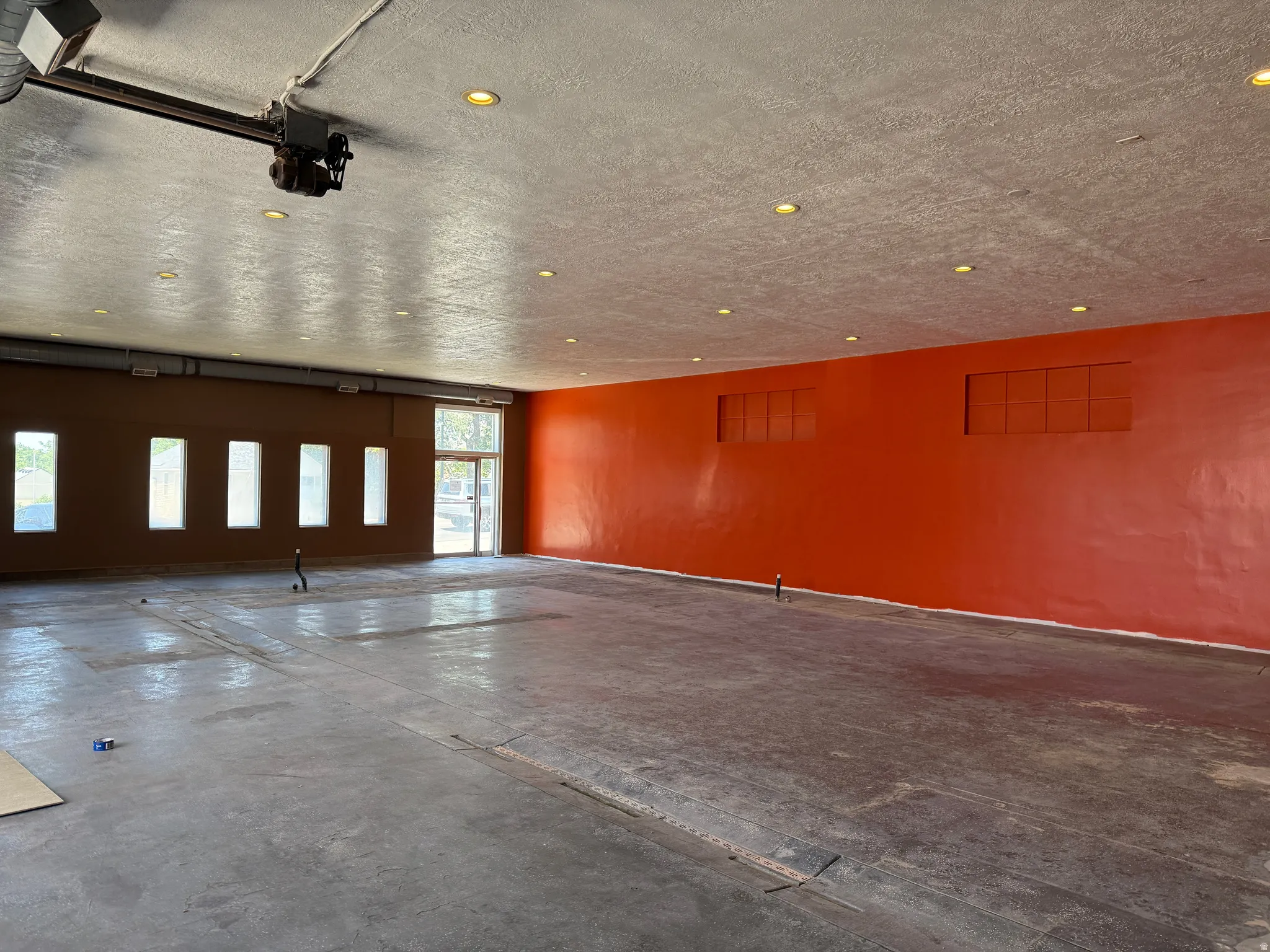 Spacious interior featuring a concrete floor, recessed lighting, high ceilings, and a large front entrance with glass panels