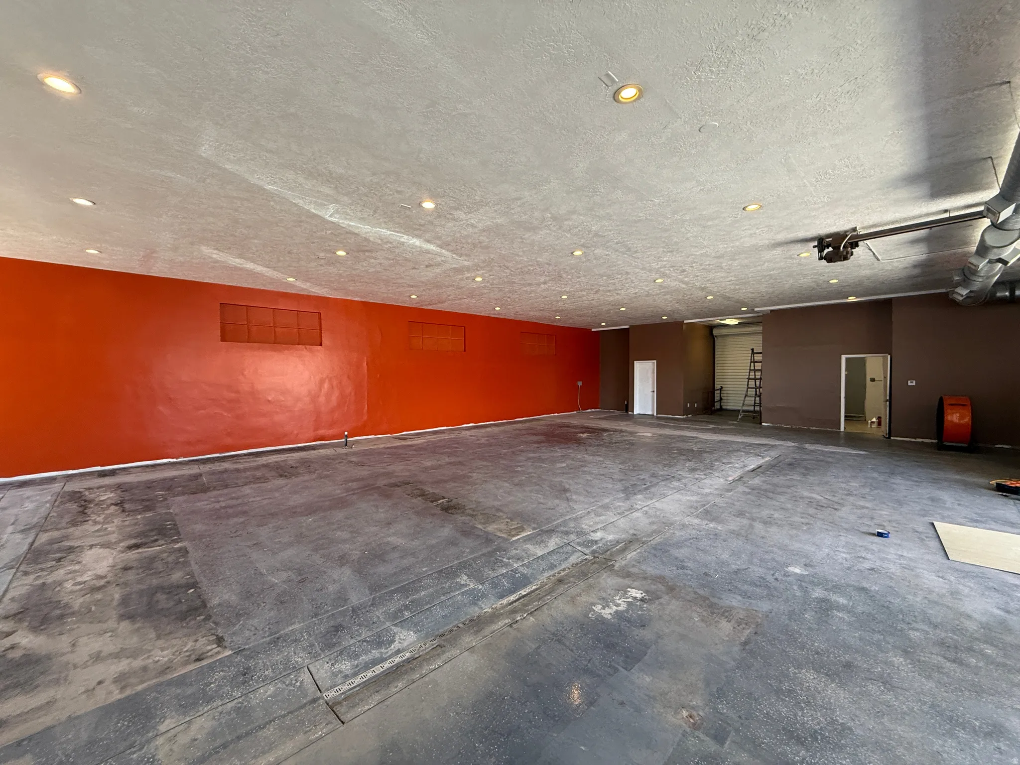 Expansive open-concept space featuring concrete flooring and a high ceiling with recessed lighting