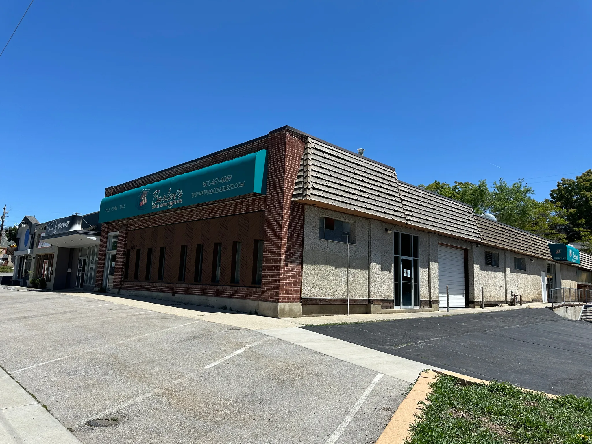 Commercial building featuring a brick facade with a teal awning, multiple window openings, and a prominent garage door
