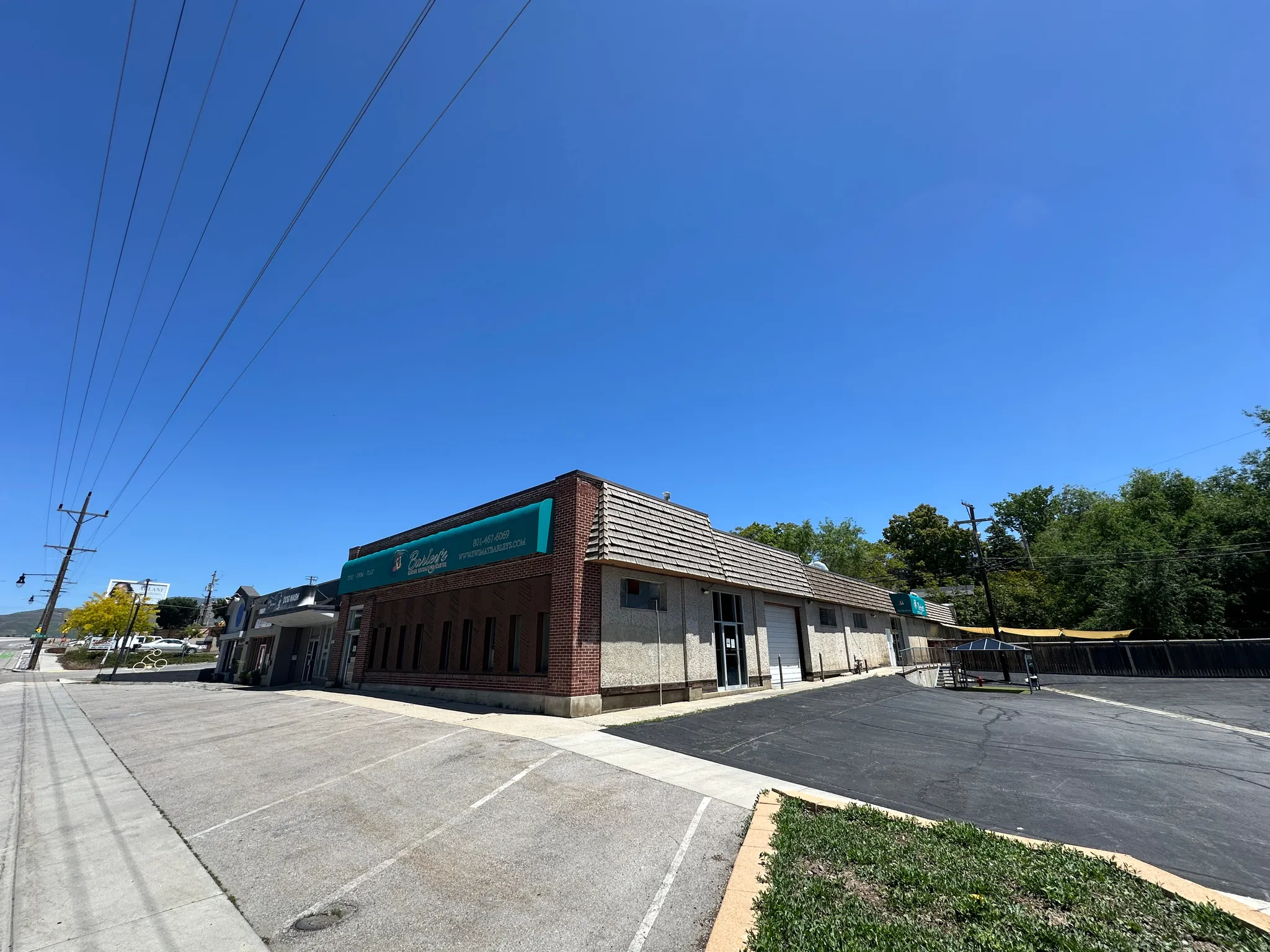 Commercial building featuring a brick facade with horizontal windows, a teal awning, and a textured roof