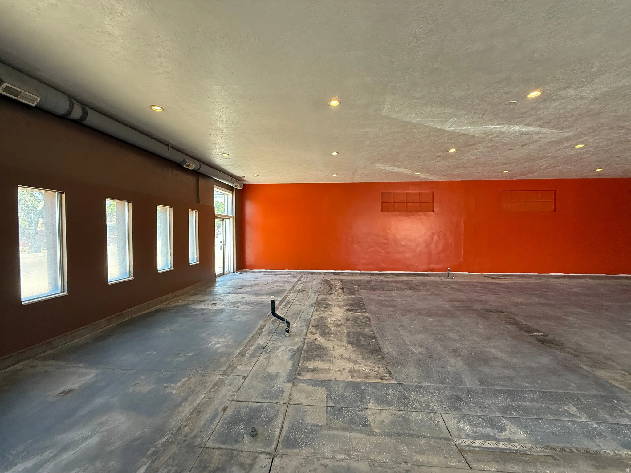 Spacious interior room featuring a large open floor plan and exposed ceiling ductwork