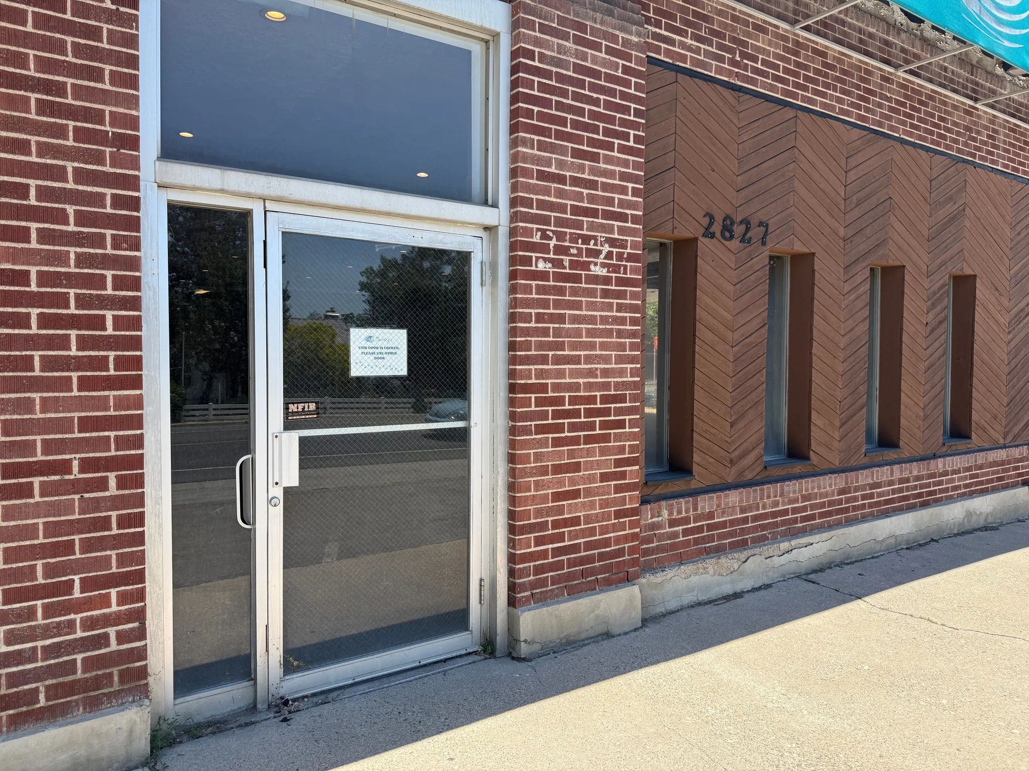 Brick and wood-finish facade featuring a glass entry door with transom window, aluminum framing, and recessed lighting