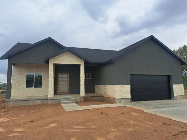 Modern single-story residence featuring a dark gray stucco exterior with light-colored stacked stone accents