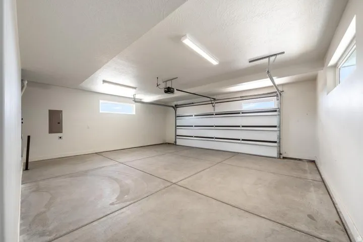 Spacious garage featuring a concrete floor, overhead lighting, and white walls