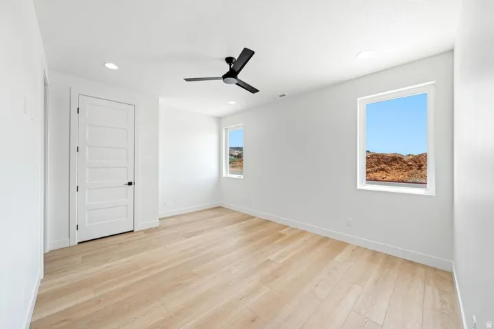 Spacious room featuring light wood-finish flooring, recessed lighting, and a modern black ceiling fan