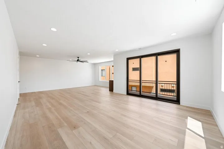 Spacious room featuring light wood-finish flooring, recessed lighting, and a modern ceiling fan
