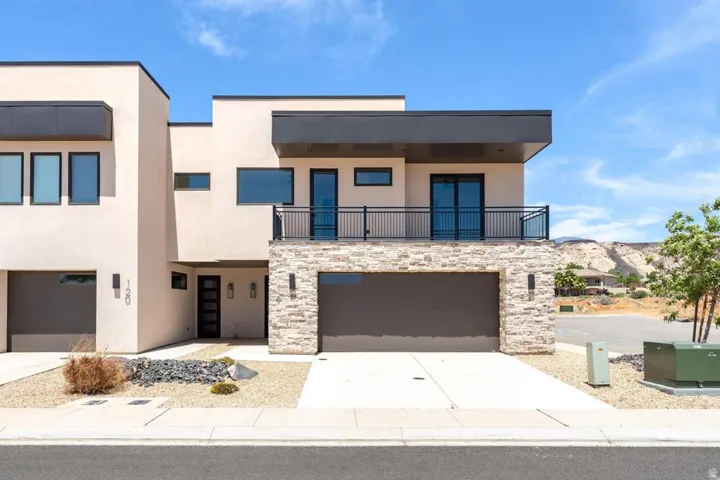 Modern stucco exterior with stone veneer accents, flat roofline, and multiple garages