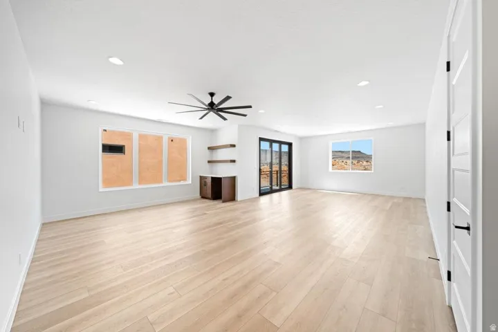 Spacious room featuring light wood-finish flooring, recessed lighting, and a contemporary ceiling fan