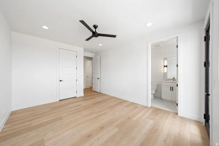 Spacious room featuring wood-finish flooring, a contemporary ceiling fan, recessed lighting, and white paneled doors with black hardware