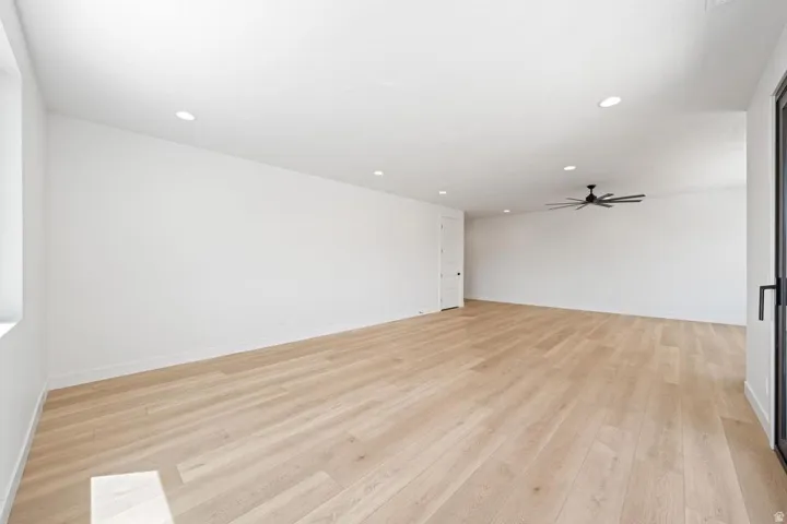 Spacious room featuring light wood-finish flooring, recessed lighting, and a contemporary ceiling fan