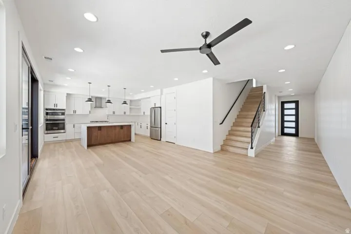 Open-concept living area featuring light wood-finish flooring, recessed lighting, and a contemporary ceiling fan