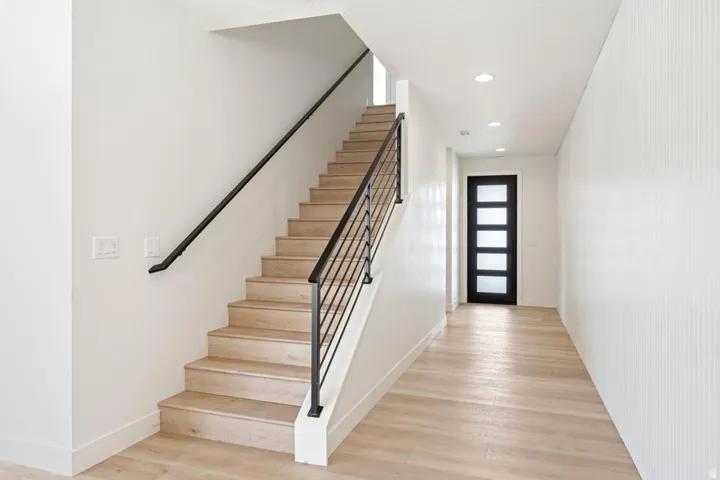 Entryway featuring a modern staircase with light wood-finish treads and risers, black metal balusters, and a black handrail