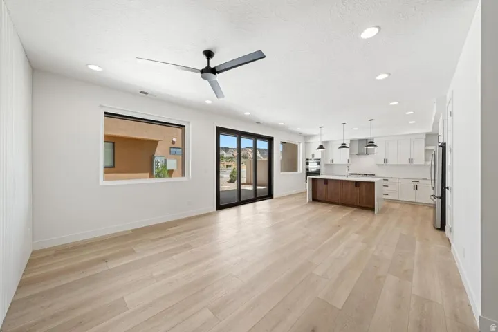 Open-concept living space featuring light wood-finish flooring, recessed lighting, and a modern ceiling fan