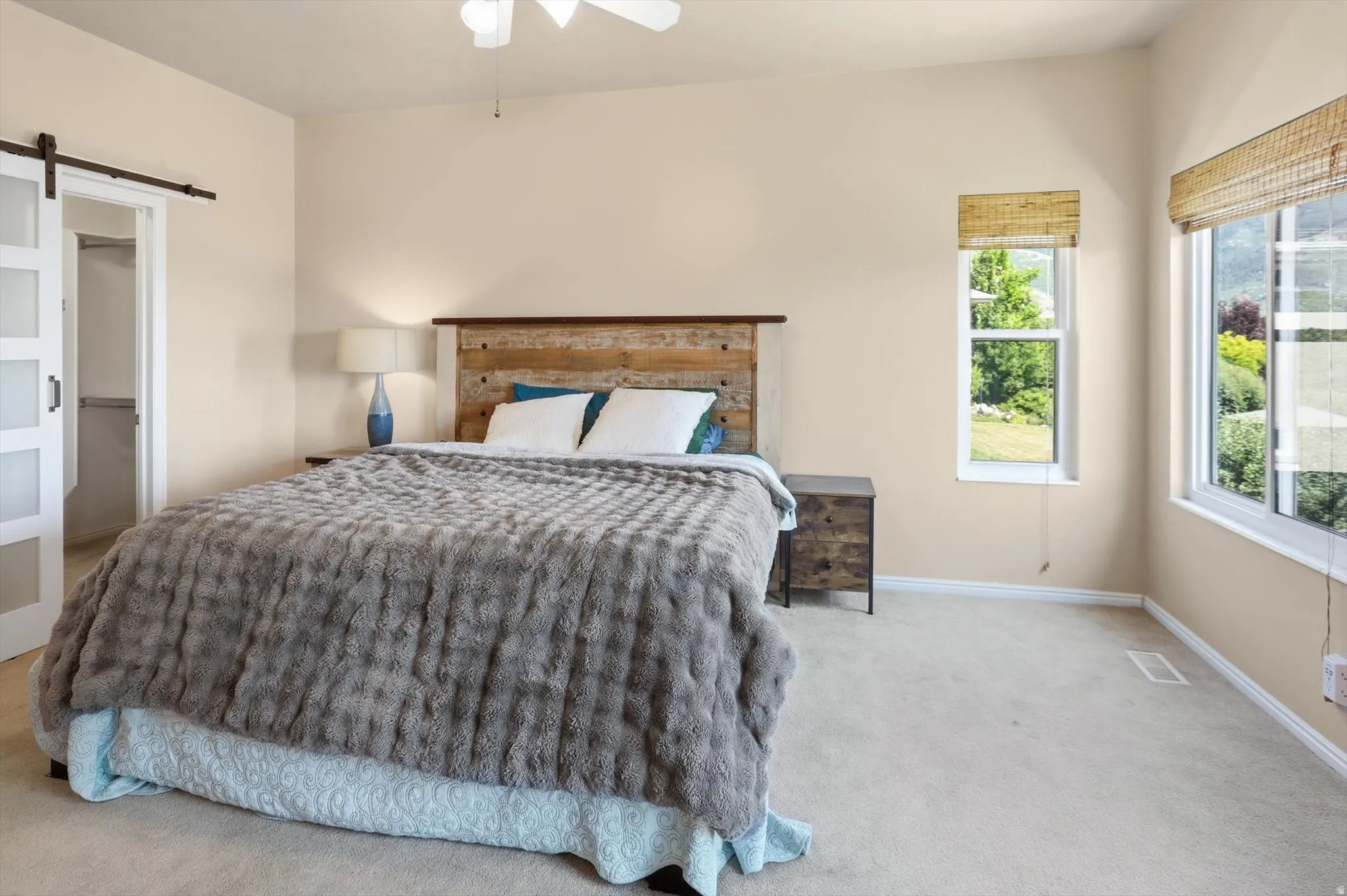 Spacious bedroom featuring light neutral wall paint and carpeting