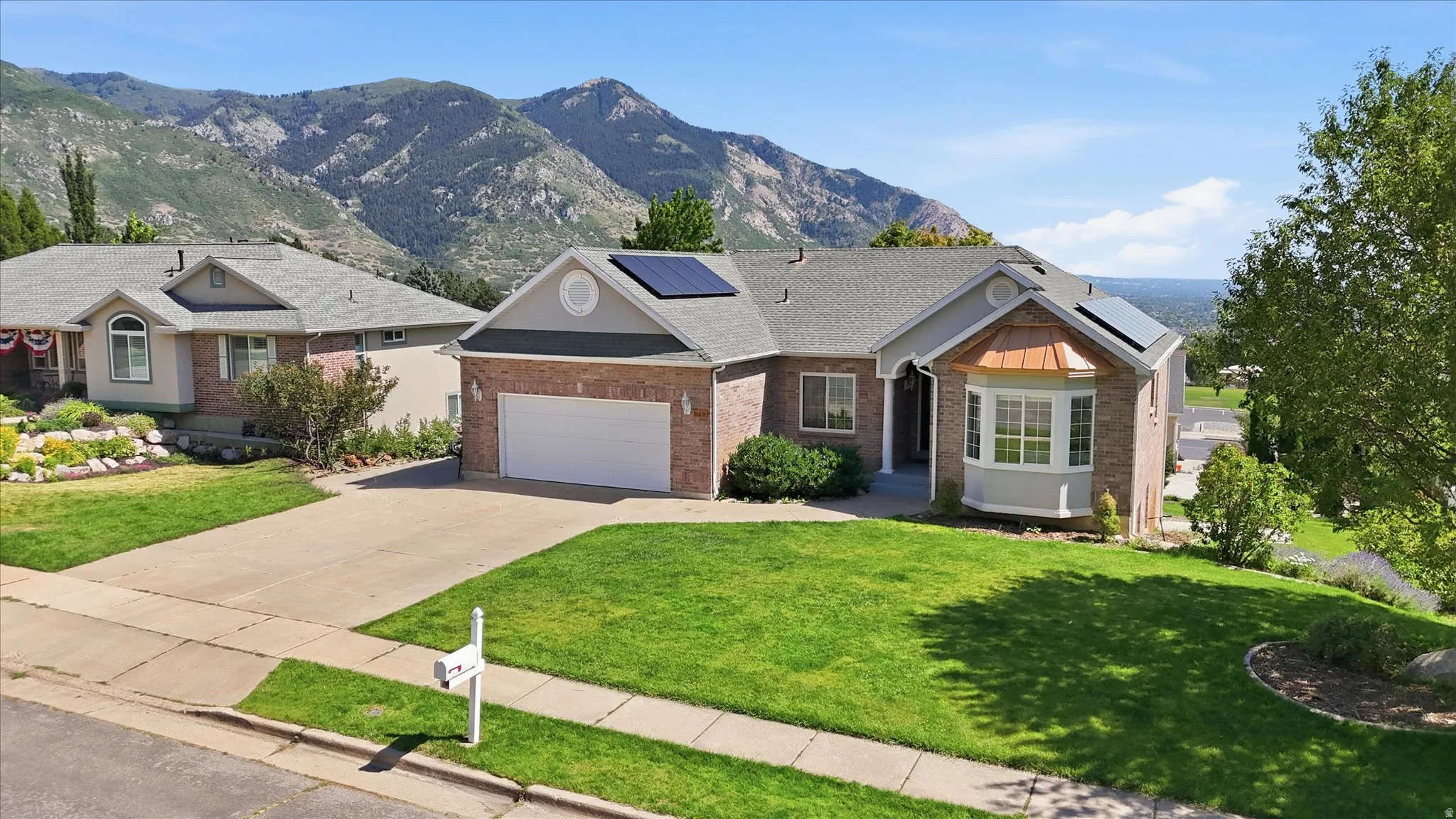 Brick and siding exterior featuring a bay window with a copper-colored accent roof, an attached garage, and solar panels on the roof